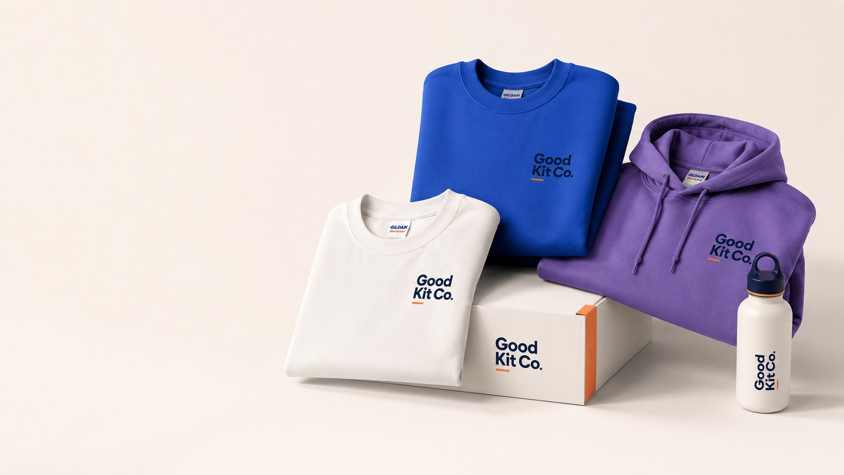 Good Kit Co Starter Pack: a folded cream T-shirt, blue sweatshirt and purple hoodie with a cream branded box and water bottle, each printed with the Good Kit Co logo